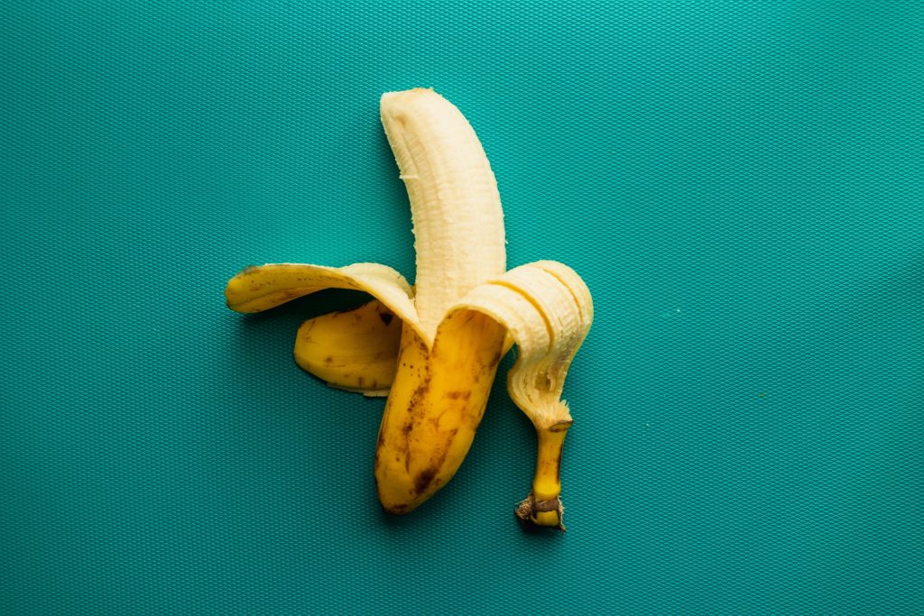 Half peeled banana on a green backgound