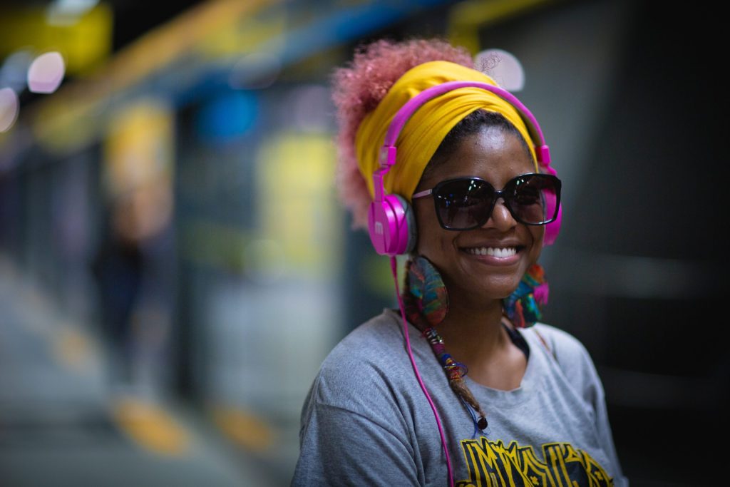 Smiling women wearing headphones on a train platform