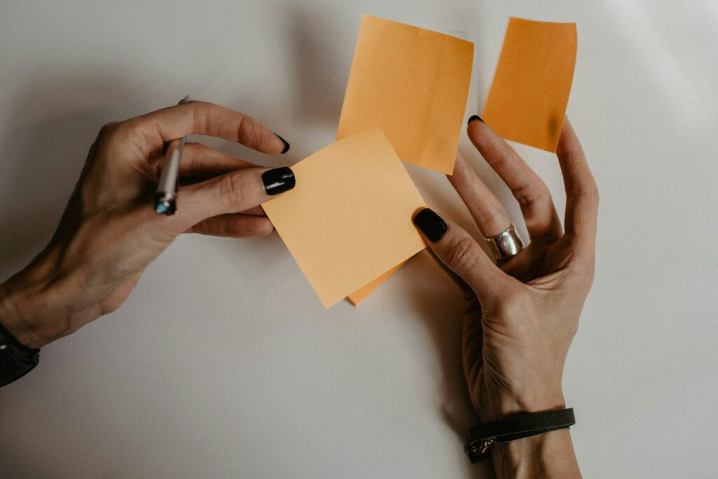 Hands holding three blank post-it notes and a pen